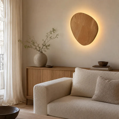 Applique murale effet bois Sève, variante ovale, diffusant un halo doux dans un salon français aux matières naturelles.