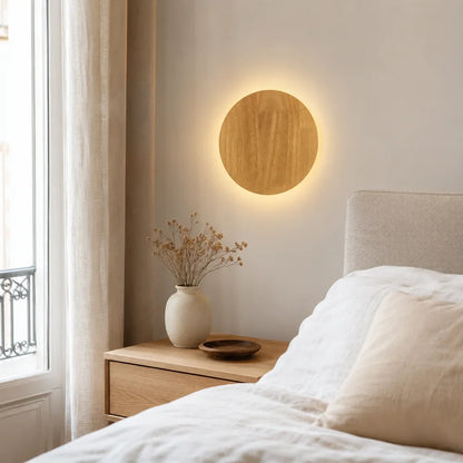 Applique murale effet bois Sève, variante ronde, installée près du lit dans une chambre française naturelle et lumineuse.